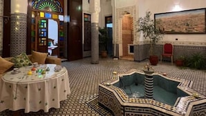 A spacious interior with a checkered floor, a central fountain, and a dining area with a round table. - Riad Dar Babouche (Fes)