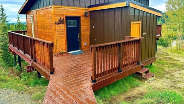 Une cabane avec une façade en bois, une porte d’entrée, un petit porche et une terrasse.
