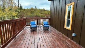 Une terrasse en bois avec deux chaises bleues et une petite table.
