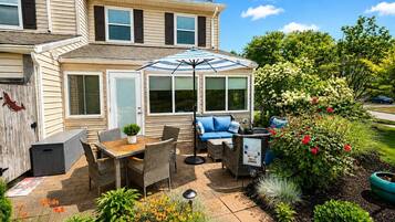 Eine Terrasse mit Gartenmöbeln, einer überdachten Sitzgelegenheit und verschiedenen Pflanzen und Blumen.