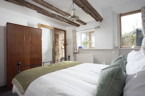 A bedroom with a bed, wooden wardrobe, stone wall, window with flowers, and exposed wooden beams. - An Selder - Near waterfront, pet allowed, Wifi (Fowey)