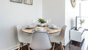 Uma área de refeições com uma mesa redonda, cadeiras brancas e um lustre moderno.