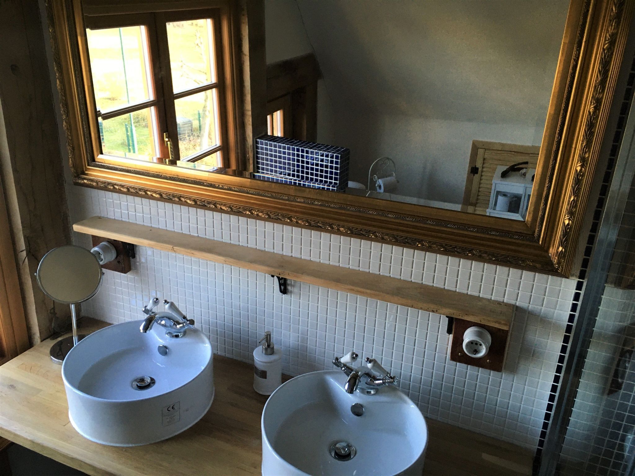 A bathroom with two sinks, a mirror, and a window.