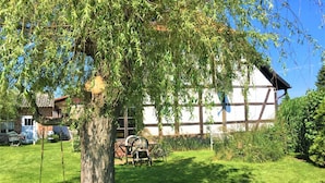 Une maison traditionnelle à colombages, avec un portique et une pelouse au premier plan.