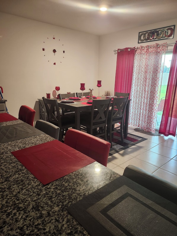 Un coin repas avec une table dressée pour quatre personnes, entourée de chaises.