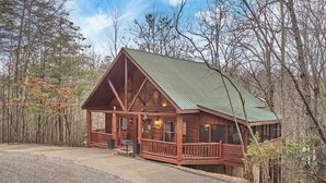 A wooden cabin with a green roof, surrounded by trees. - FALL FOLIAGE RETREAT! 1BR+Loft Cabin w/Hot Tub & Arcade (Sevierville)