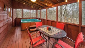 A wooden deck with a hot tub, a table with chairs, and a ceiling fan. - FALL FOLIAGE RETREAT! 1BR+Loft Cabin w/Hot Tub & Arcade (Sevierville)