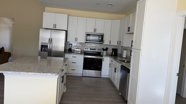 A modern kitchen with white cabinets, stainless steel appliances, and a granite countertop. - Superb 4-bedroom house with AC in charming Loris (Loris)