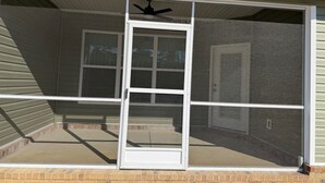 A screened porch with a ceiling fan, a sliding glass door, and a brick foundation. - Superb 4-bedroom house with AC in charming Loris (Loris)