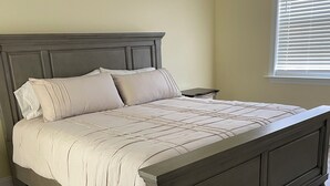 A bed with a headboard, a bedside table, and a window with blinds. - Superb 4-bedroom house with AC in charming Loris (Loris)