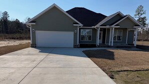 A two-story house with a garage, a covered porch, and a driveway. - Superb 4-bedroom house with AC in charming Loris (Loris)