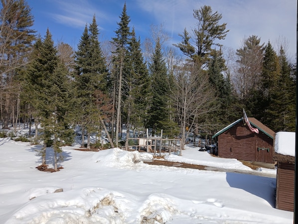 A snowy landscape with a wooden cabin and a fenced area.