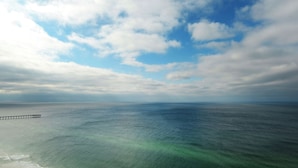 Un muelle se adentra en un mar tranquilo bajo un cielo parcialmente nublado.