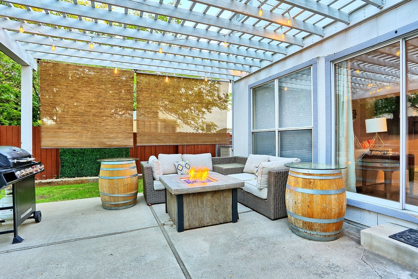 Un patio couvert avec des meubles d’extérieur, un barbecue et un foyer.
