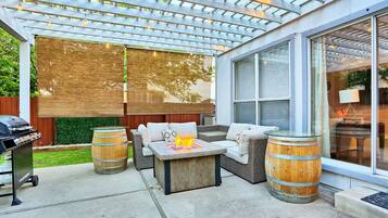 Un patio couvert avec des meubles d’extérieur, un barbecue et un foyer.