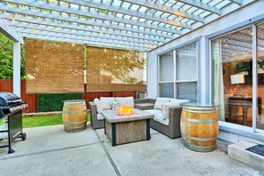 A covered patio with outdoor furniture, a grill, and a fire pit.