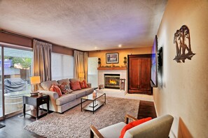 A living room with a fireplace, sofa, coffee table, and a TV mounted on the wall.