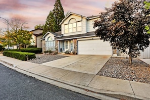 A two-story house with a garage, a driveway, and a well-maintained lawn.