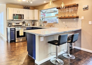 A kitchen with a large island, bar stools, and a window with a view.
