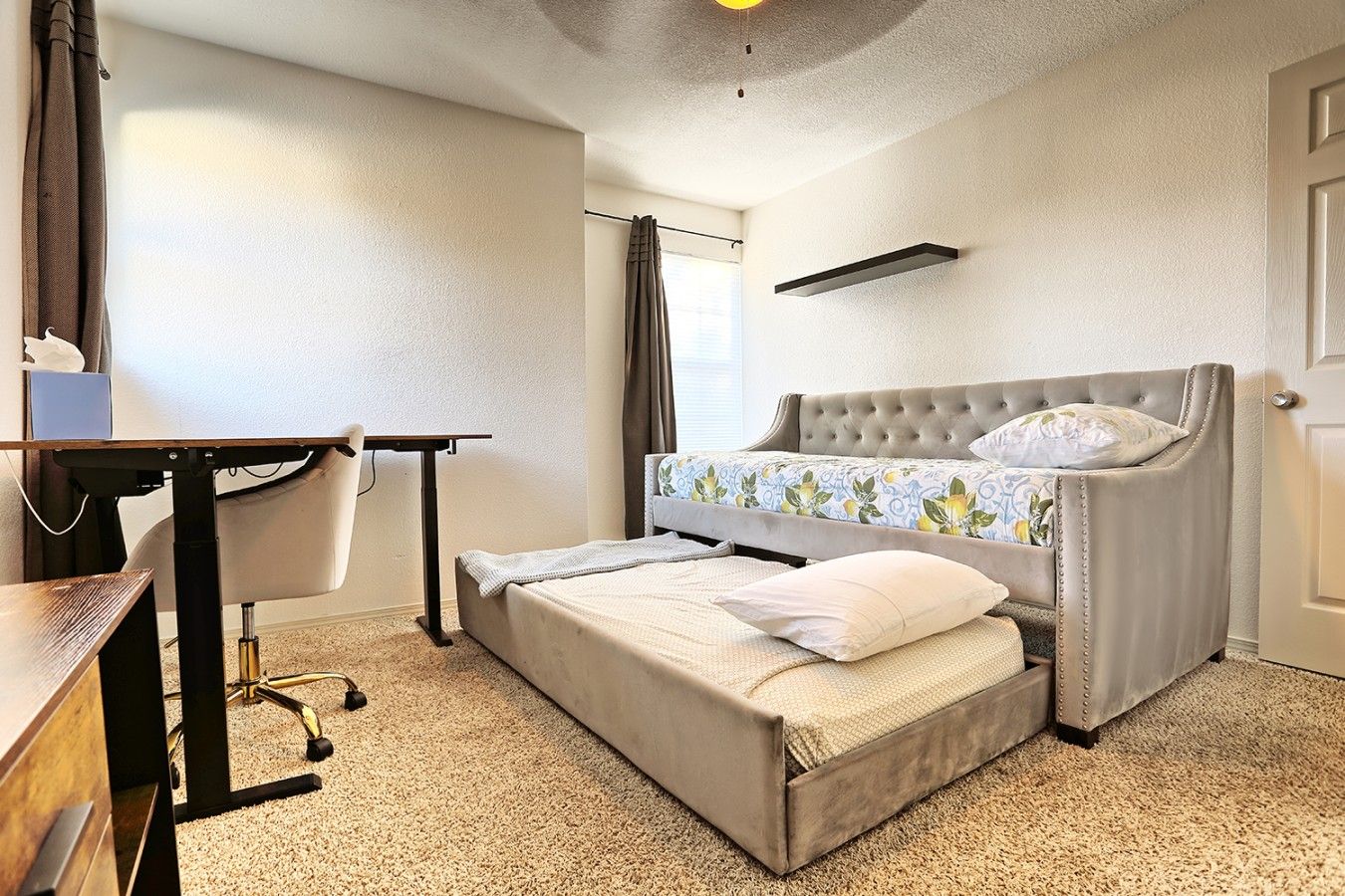 Une chambre d’hôtel avec un lit, un bureau, une chaise et une fenêtre avec des rideaux.