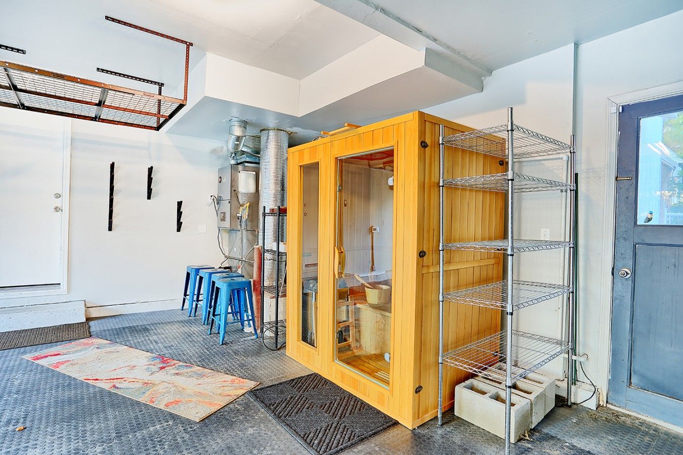 Une pièce avec un meuble en bois, des étagères en métal et une porte dotée d’une fenêtre.