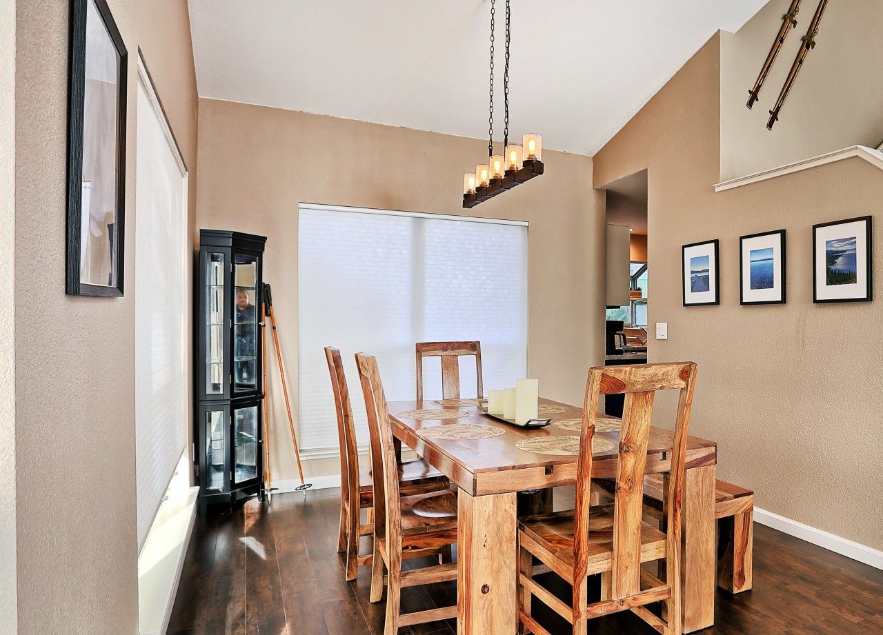 Un coin repas avec une table et des chaises en bois, un lustre et des tableaux encadrés accrochés au mur.