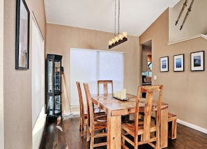 Un coin repas avec une table et des chaises en bois, un lustre et des tableaux encadrés accrochés au mur.