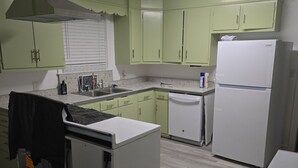 A kitchen with light green cabinets, a white refrigerator, and a dishwasher. - Serene vintage 3b/2ba  home with AC. Medical professions MD, NP, RN are welcome. (Valdosta)