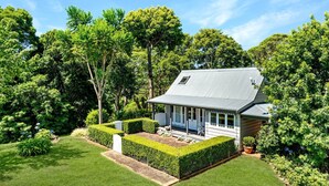 Une maison dotée d’un porche abrité, entourée d’arbustes et d’arbres bien entretenus.