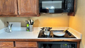 A kitchen with wooden cabinets, a microwave, a stove, and a dishwasher. - Blue Cottage with a garden tub. Walking distance to TCU. Near the Zoo & Dickies (Fort Worth)