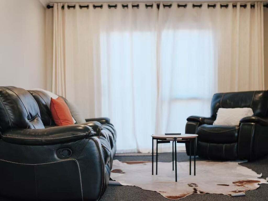 A living room with a leather sofa, a leather armchair, and a small table.