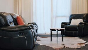 Ein Wohnzimmer mit einem Ledersofa, einem Ledersessel und einem kleinen Tisch.
