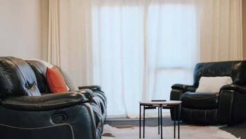 A living room with a leather sofa, a leather armchair, and a small table.