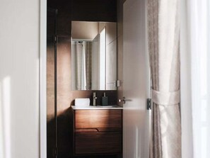 Een badkamer met een houten wastafel, een spiegel en een handdoek aan de muur.
