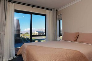 Une chambre avec un grand lit, une vue sur les montagnes et un balcon.