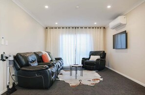 A modern living room with a leather sofa, a leather armchair, a small round table, and a cowhide rug. - Heavenly Tekapo 4bdr4ba (Lake Tekapo)