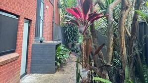 A red brick building with large windows and a narrow pathway leading to a tree-lined area. - A Cozy 1BR in Cronulla – Walk to Beach & Shops U4 (Cronulla)