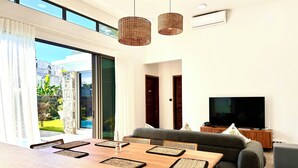 Uma sala de estar moderna com uma grande mesa de jantar de madeira, um sofá e uma televisão.