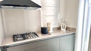 Cozinha moderna com fogão a gás, cafeteira e chaleira na bancada.