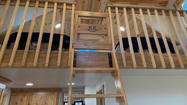 Ein Holzinnenraum mit einer Schlafhöhenlage, einer Holztreppe und einer Decke mit freiliegenden Balken.