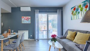Una sala de estar moderna con comedor, sofá gris y vistas a través de un ventanal.