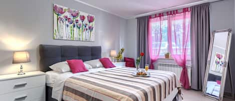 Une chambre moderne avec un lit, des tables de chevet, une commode, un miroir et une fenêtre avec des rideaux.