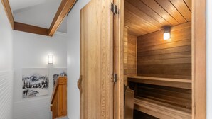Uma sauna de madeira com teto inclinado e luminária.