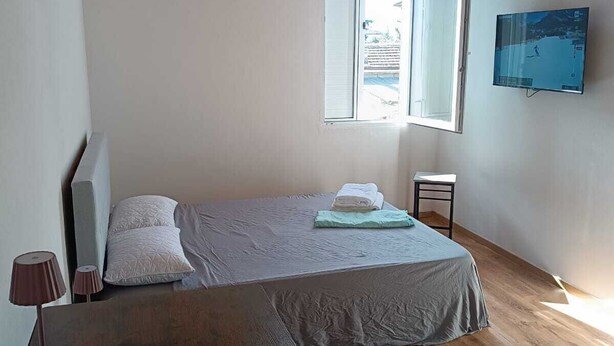 A bedroom with a bed, a TV, a window, and a wooden ceiling. - MTB b&b (Alfonsine)