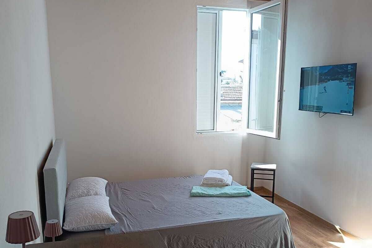 Ein Schlafzimmer mit einem Bett, einem Fernseher, einem Fenster und einer Holzbalkendecke.