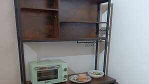 A kitchenette with a built-in microwave, a small sink, and a shelf with a bowl of salad and a sandwich. - MTB b&b (Alfonsine)