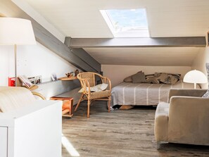A cozy attic bedroom with a skylight, a bed with pillows, a chair, a desk with a lamp, and a bookshelf. - Barasteguia by Interhome (Saint-Jean-de-Luz)