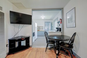Una cocina moderna con zona de comedor, un televisor de pantalla plana y un pequeño escritorio negro.