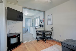 Een moderne keuken met een eethoek, een flatscreen televisie aan de wand en een zithoekje met een tafel en stoelen.