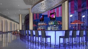 Zona de bar moderna con mostrador, varias sillas y una amplia variedad de botellas.